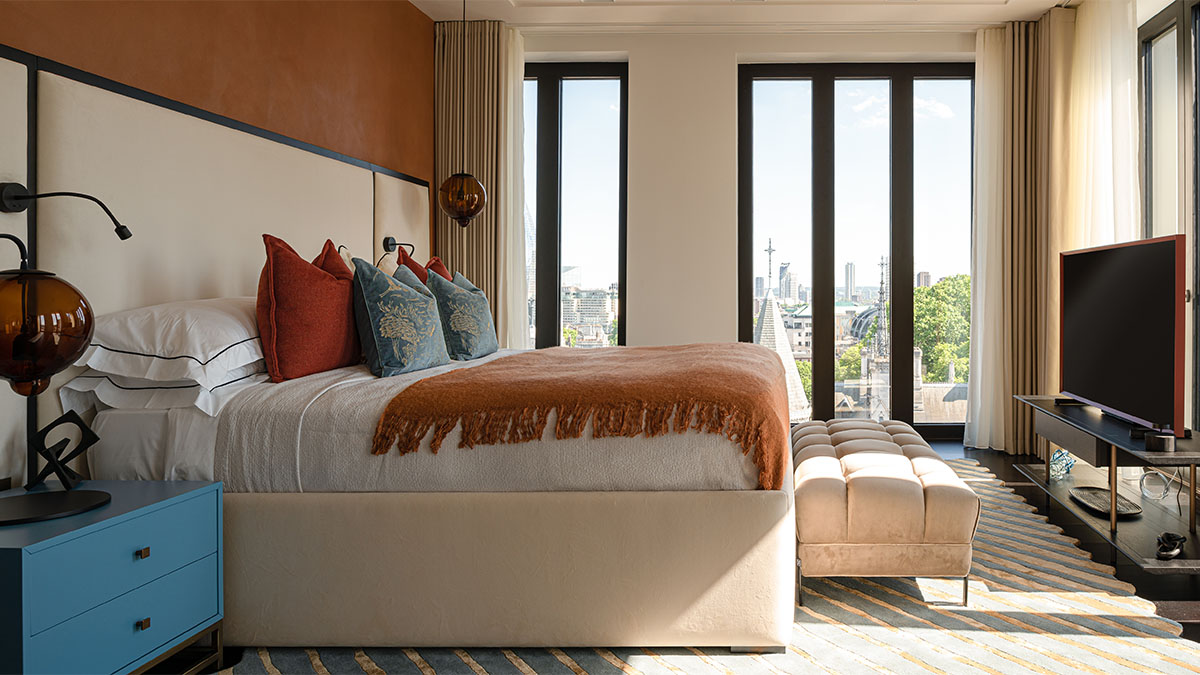 Beige bed with orange throw, city view, TV