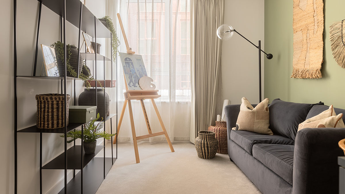 Professional furnishing and staging in a London flat living room. An easel with a painting, plush sofa, and bookshelf add appeal